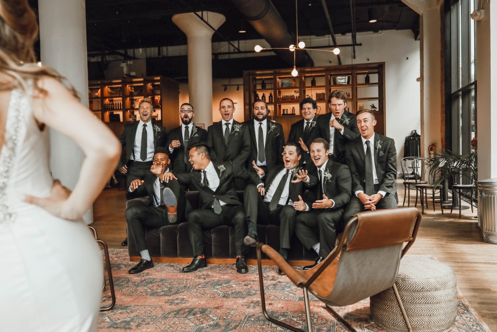 a fun picture of the bride showing the groomsmen her dress