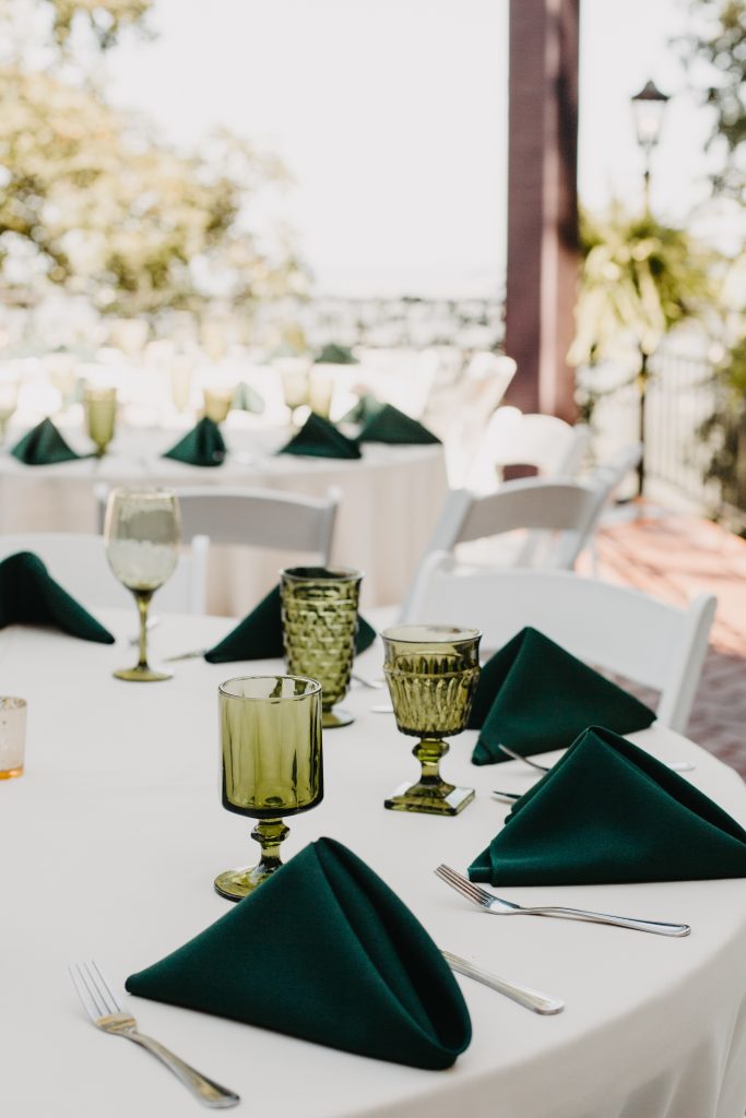 Tablescape at mountain boho wedding featuring green glass goblets and green folded napkins.