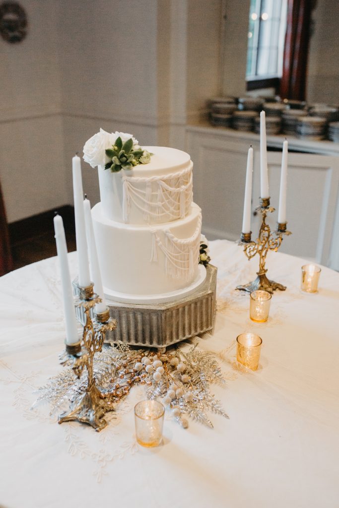 Beautiful boho macrame detail on a wedding cake with gold candlesticks.