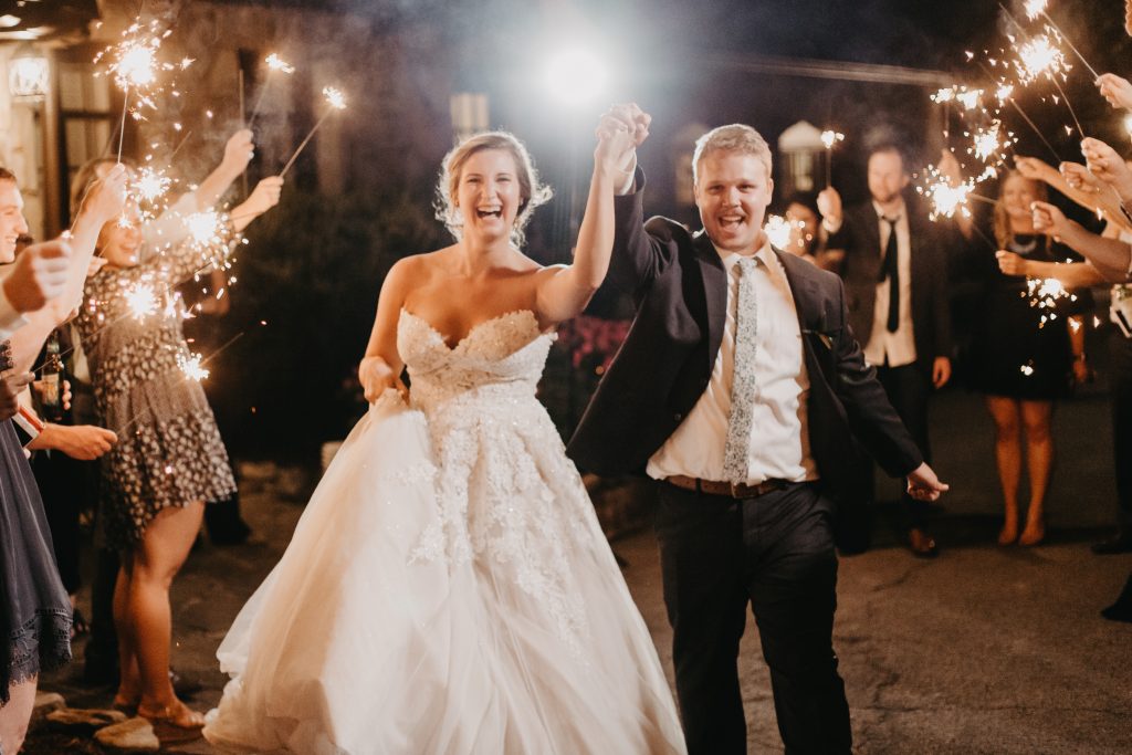 Bride and groom running through sparklers as they leave their boho mountain wedding!