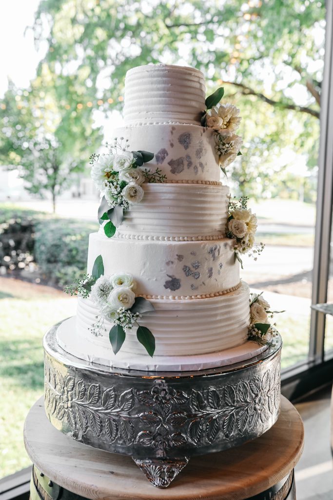 A fun five tiered cake with silver and flower details.