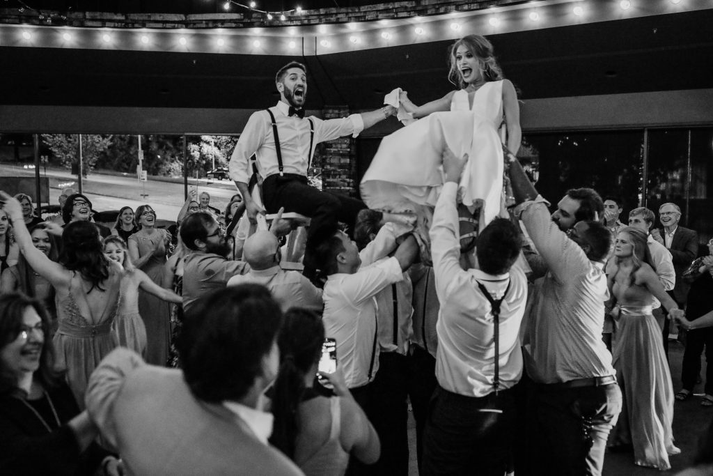 A bride and groom being hoisted into the air with shocked faces during the traditional jewish chair dance.