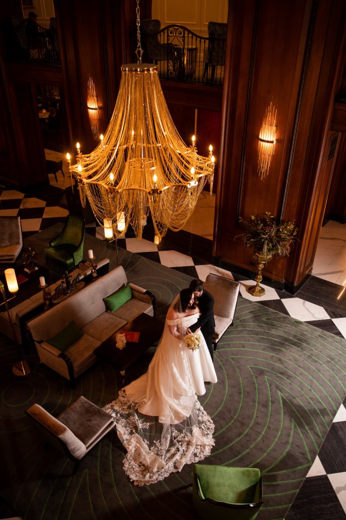 A Bride and groom shot from the upper level looking down under the chandelier.