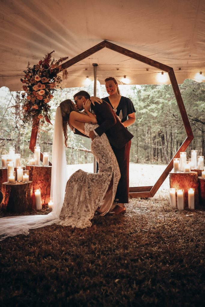 The first kiss under the twinkle lights of a tent at a boho glam wedding.