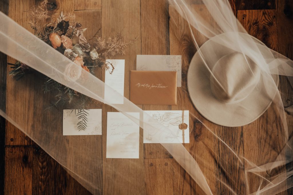 Invitations, flowers, and hat are arranged beautifully under a veil.