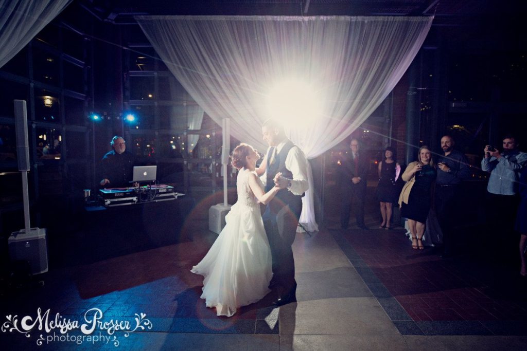 Bride and groom share their first dance while a dj sets the mood.