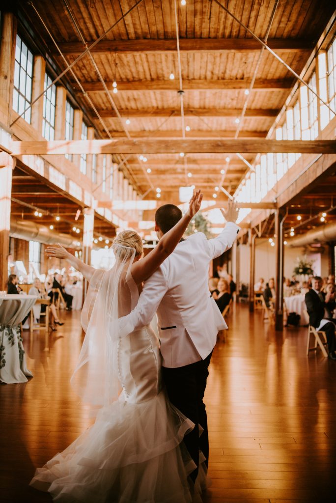 A picture of the bride and groom with their arms out and around each other as the reenter their party for the reception of their industrial chic wedding.