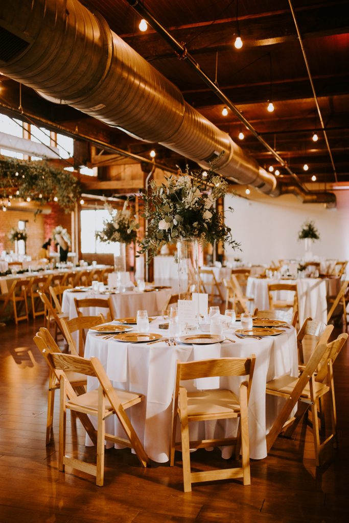 The high centerpieces with glass pillars help this industrial wedding venue feel chic!